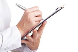Hand filling out checklist on clipboard